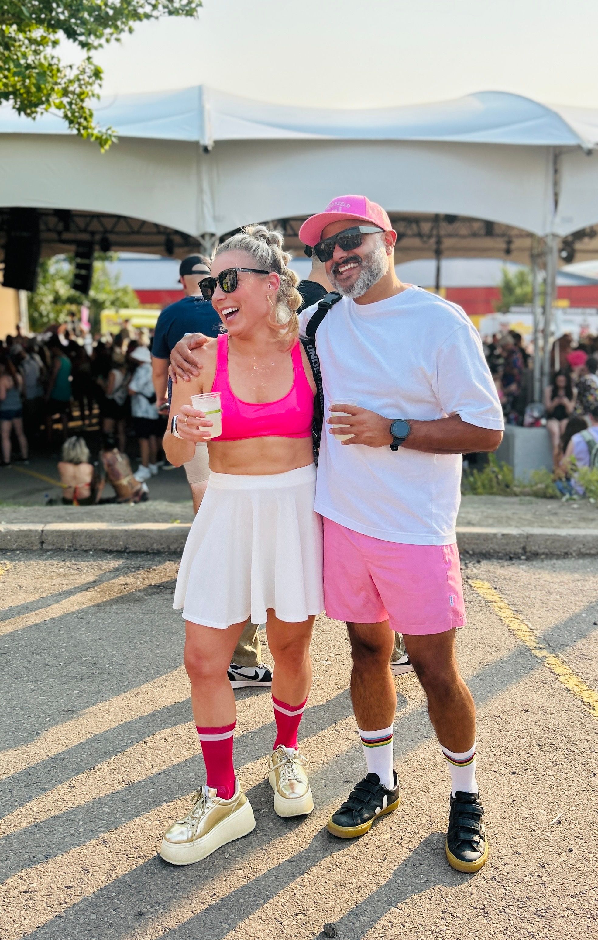 Angie and Uday laughing together in the evening sun, both dressed in pink and white